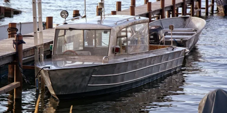 A sleek metal boat moored at a scenic wooden dock on a clear day