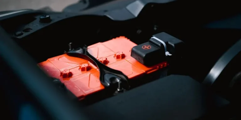 Detailed view of an orange car battery inside a vehicle's engine bay