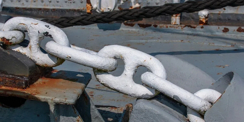 Detailed view of a weathered anchor chain on a docked ship, showing rustic textures and maritime usage