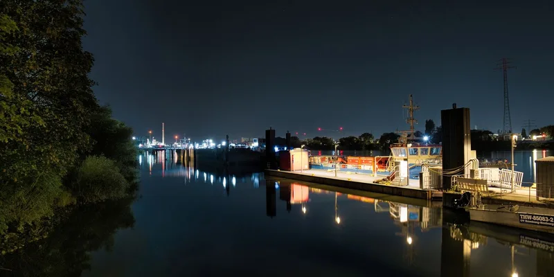 Serene nighttime view of a harbor with boats and lights reflecting on water