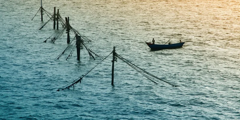 Fishing boat and poles in calm sea waters during sunset near Vũng Tàu, Vietnam