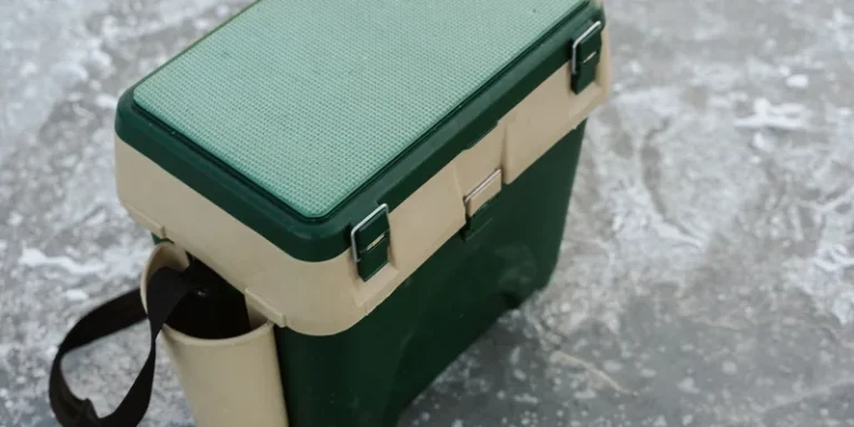 A green and beige cooler sits on a frozen ice surface