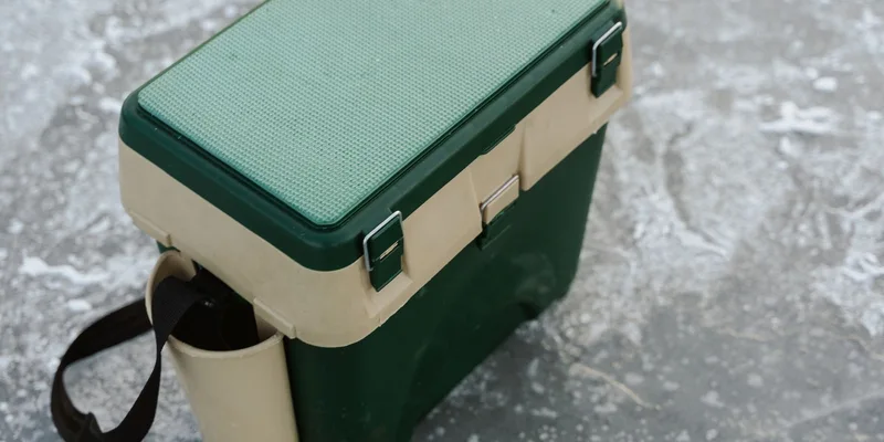 A green and beige cooler sits on a frozen ice surface