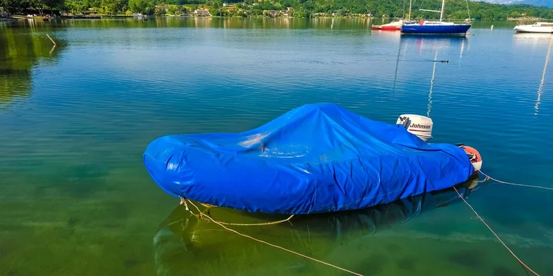 A boat covered in blue tarp floating on calm water with scenic green hills in Piedmont, Italy