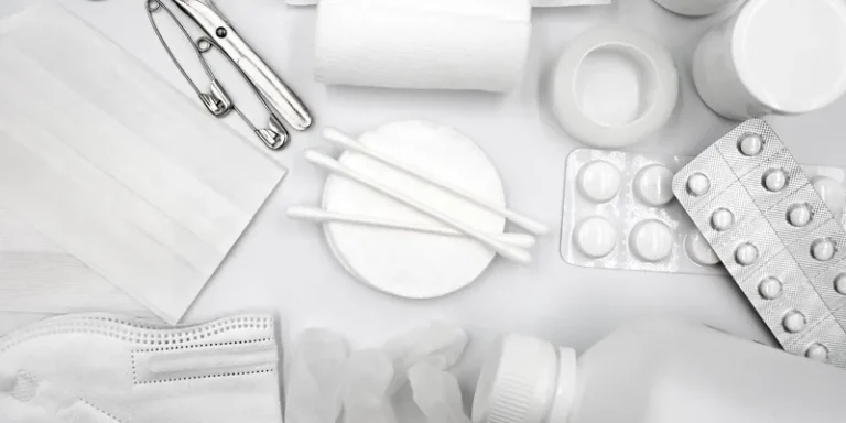 A flat lay of essential first aid supplies including bandages, gloves, and medications