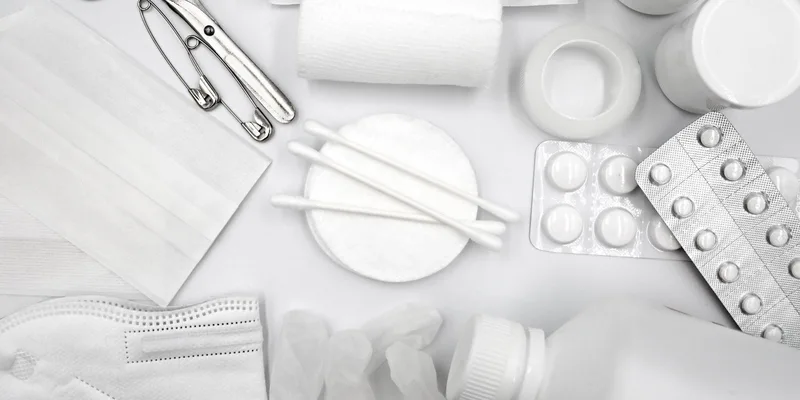 A flat lay of essential first aid supplies including bandages, gloves, and medications