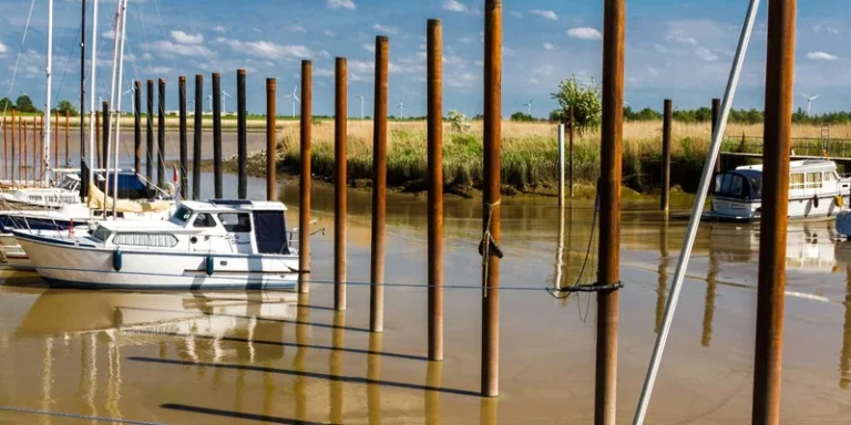 Scenic view of boats moored by wooden poles on a calm day in Jemgum, Lower Saxony, Germany