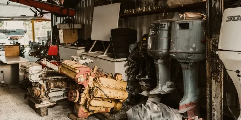 Interior of a workshop featuring engines, machinery, and outboard motors in a rustic setting