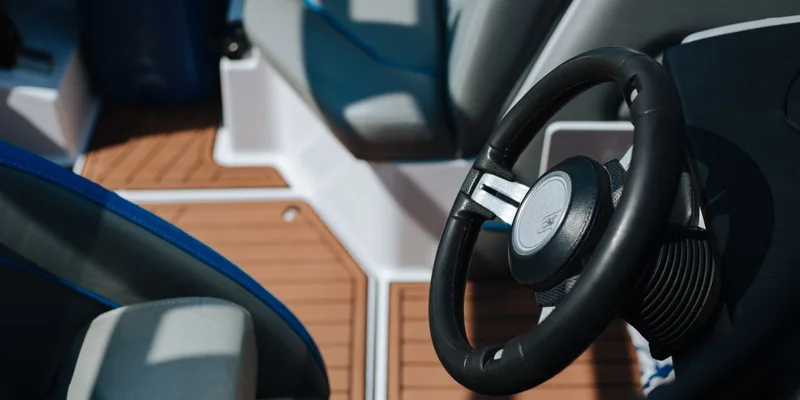Detailed view of a boat's steering wheel and deck seating under sunlight outdoors