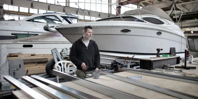 Mechanic repairing boats in an industrial workshop with a focus on yacht maintenance