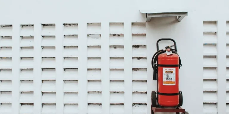 Minimalist image of a red fire extinguisher mounted on a white wall, emphasizing safety