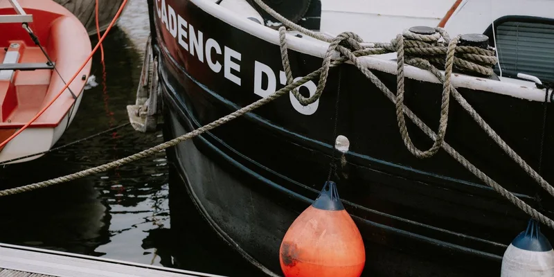 Detail view of boats moored at a marina dock with colorful buoys and nautical ropes