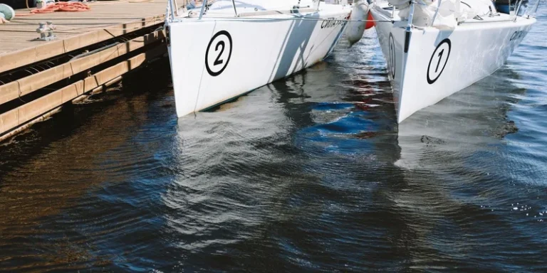 Twin yachts with numbered hulls docked at a marina