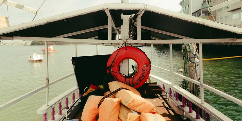 Boat deck featuring life jackets and a lifebuoy on a calm waterway