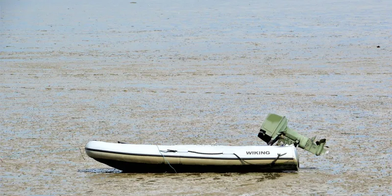 A motorboat with outboard engine stranded on a mudflat in Neuharlingersiel, Germany