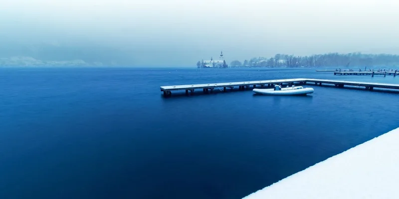 Serene winter lake scene with snow-covered dock and pontoon boat