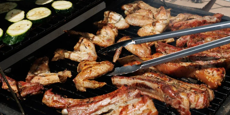 Delicious barbecue chicken and zucchini grilling outdoors on a sunny day