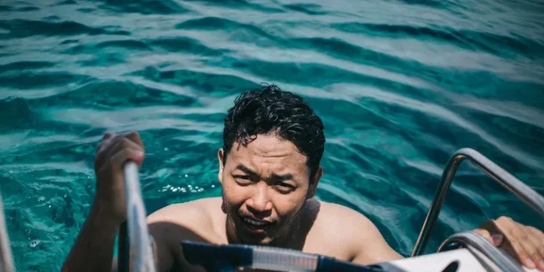 Adult male climbing a ladder after swimming in clear tropical waters under a sunny sky