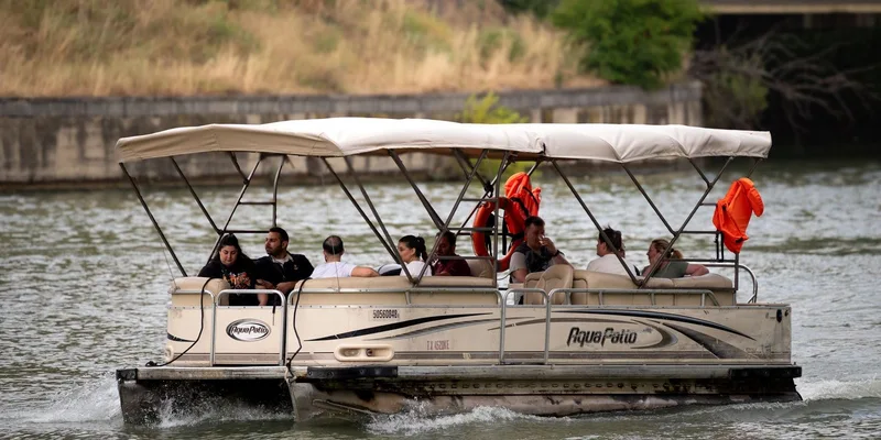 Pontoon boat cruising on a river with diverse passengers enjoying a sunny day in Tbilisi