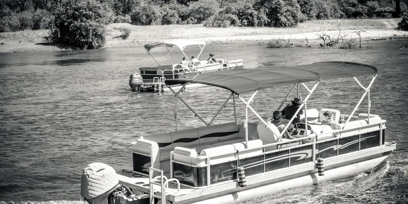 Pontoon boats cruising on a scenic river in monochrome