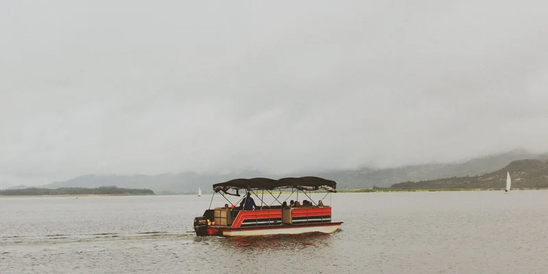 A peaceful pontoon boat ride on a tranquil lake under a cloudy sky