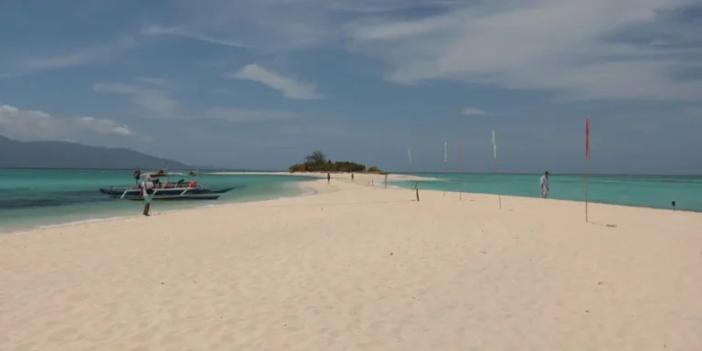 Stunning sandbar view with traditional Filipino boat, clear turquoise water, white sand, under a bright sky