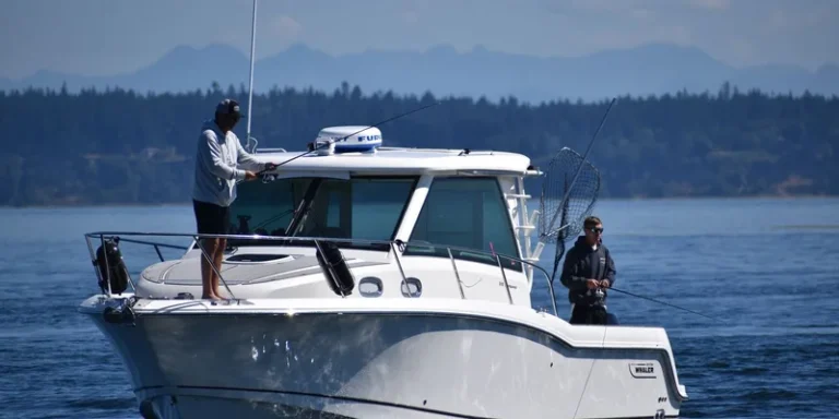 Two fishermen on a motorboat fishing at a serene lake with a forested mountain backdrop