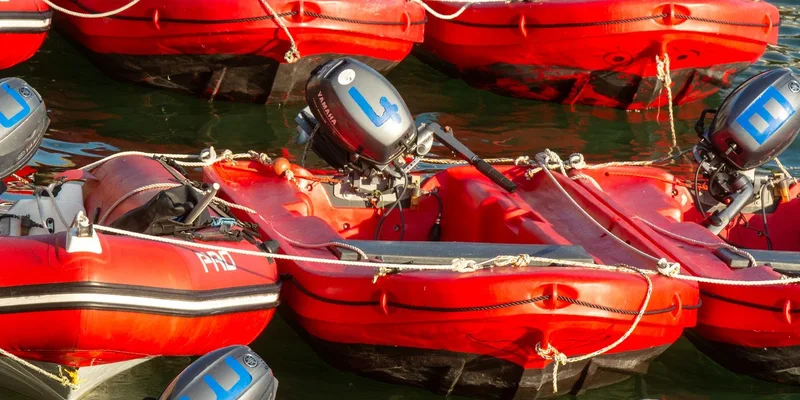 Docked red inflatable boats equipped with outboard motors, ready for use on the water