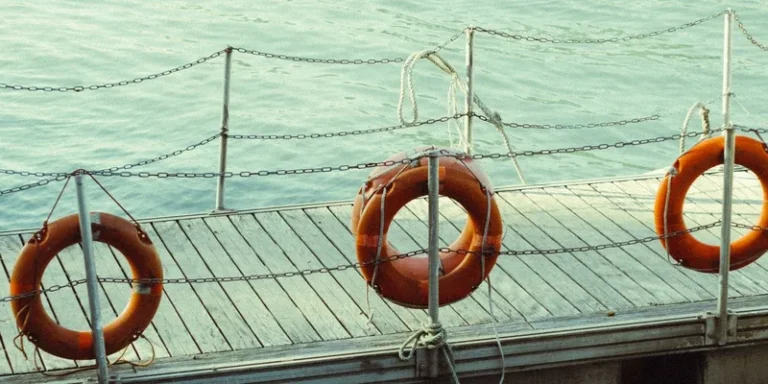 Three life rings hang on a dock by the tranquil sea