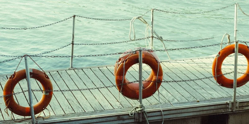 Three life rings hang on a dock by the tranquil sea